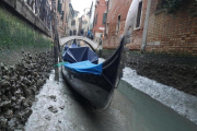 Una gondola permanece amarrada en un canal practicamente sin agua en Venecia.-ANDREA MEROLA