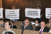 Trabajadores municipales portan pancartas pidiendo una negociación del seguro médico durante el debate plenario sobre este asunto. / V.GUISANDE-