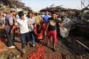 Un grupo de hombres evacúa el cuerpo sin vida de una víctima del atentado perpetrado con un caimión bomba en el mercado de Yamila.-AP / KARIM KADIM