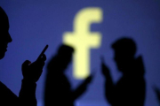 Unos usuarios de Facebook, ante el logotipo de la red social.-DADO RUVIC / REUTERS