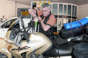 Un trabajador de una gasolinera llenando el depósito de una moto.-MONICA TUDELA