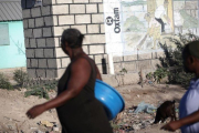 Dos mujeres pasan ante un mural de Oxfam en Puerto Príncipe, Haití.-ANDRES MARTINEZ CASARES (REUTERS)