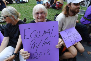 Una australiana pide igual salario para mujeres y hombres, junto a un joven que subraya que es una lucha de todos, en la concentración del Día de la Mujer en Melbourne.-EFE / JOE CASTRO