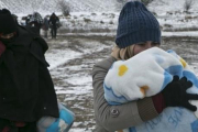 Una mujer migrante protege a su hijo con una manta mientras camina cerca de Miratovac (Serbia), este lunes.-AP / VISAR KRYEZIU
