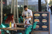 Un camarero sirve a unos clientes en una terraza.-DANNY CAMINAL