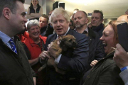 El primer ministro británico, Boris Johnson, sostiene un perro durante un encuentro con Paul Howell, el recién elegido diputado del Partido Conservador en Sedgefield, en el noreste de Inglaterra.-LINDSEY PARNABY (AP)