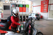 Una joven reposta carburante para su moto en una gasolinera-RICARD CUGAT