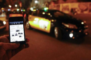Un usuario consulta la aplicación de Uber junto a la Sagrada Família, en diciembre del 2014.-AFP / QUIQUE GARCIA