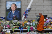 Un monje budista deja unas flores junto a la fotografía del empresario, a las afueras del estadio del Leicester.-AFP