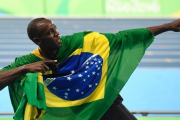 El Bolt camaleónico, envuelto en la bandera de Brasil.-AFP / ERIC FEFERBERG
