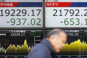 Un hombre pasa ante un cartel que exhibe las pérdidas del índice Nikkei, a la izquierda, y del Dow Jones, en una firma de valores en Tokio-YOHEI FUKAI (AP)