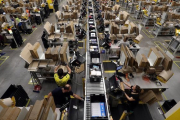 Trabajadores en una planta empaquetadora de pedidos de Amazon.-REUTERS