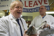 Un exultante Boris Johnson (izquierda) sostiene un salmón salvaje junto a Greg Essex, en el mercado de pescado de Billingsgate, en Londres, este miércoles.-AP / STEFAN ROUSSEAU