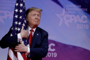 El presidente Donald Trump abrazando una bandera de su país.-REUTERS