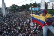 Un simpatizante de la oposición ondea una bandera venezolana ante cientos de personas congregadas para celebrar los resultados electorales en Venezuela.-REUTERS