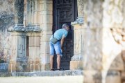 Un hombre observa el interior de la ermita del Mirón desde fuera.