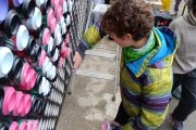 Un niño coloca una lata pintada para configurar un mural de 'mosaico' en una actividad de 'Dar la lata'.