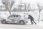 Dos personas empujan un coche durante el paso de la borrasca 'Juan'.