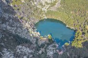 La Laguna Negra, desde el aire: un espejo glaciar oculto entre montañas, rocas y bosque espeso en el corazón del parque natural soriano