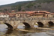 El Puente de los Carreteros, en Salduero, cruza el Duero frente a las tradicionales casonas de piedra de la comarca de Pinares.