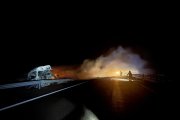Los bomberos intentan apagar el incendio del tráiler cargado de mercancías peligrosas tras sufrir un accidente.