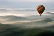 Un globo aerostático surca el cielo sobre un paisaje envuelto en niebla, evocando la experiencia única de contemplar el eclipse desde las alturas