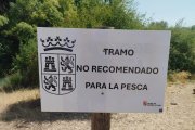 Cartel que anuncia la prohibición de pesca en el río.