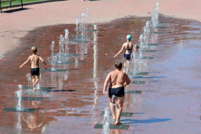 Jóvenes refrescándose en la fuente de Infantes de Lara.-ÁLVARO MARTÍNEZ