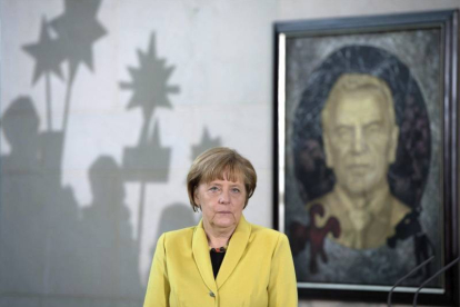 La canciller alemana, Angela Merkel, ante un retrato del excanciller Gerhard Schroeder durante una recepción, hoy, en Berlín.-Foto: EFE