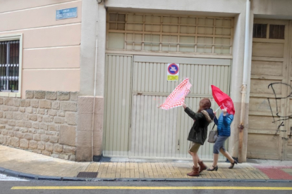 Dos jóvenes 'pelean' con sus paraguas en Soria durante un temporal de viento.-HDS