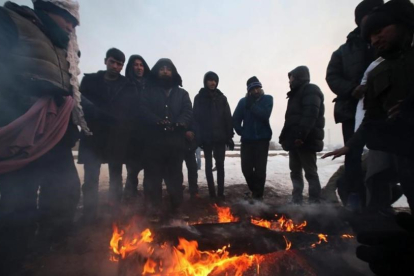 Un grupo de refugiados se protege del frio en Bergrado, Serbia.-EFE / ULEJMANOVIC