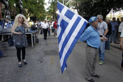 Un simpatizante del partido conservador de Nueva Democracia sale a la calle vestido de azul y con la bandera griega, a 20 días de las elecciones generales.-EFE / ALEXANDROS VLACHOS