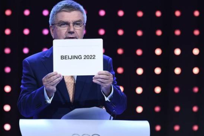 El presidente del Comité Olímpico Internacional, Thomas Bach, muestra el nombre de ciudad escogida como sede de los JJOO de invierno de 2022-Foto: AFP / MANAN VATSYAYANA