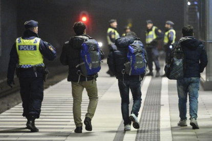 Policías suecos acompañan a dos refugiados en la estación de tren de Hyllie, en Malmo.-REUTERS / JOHAN NILSSON