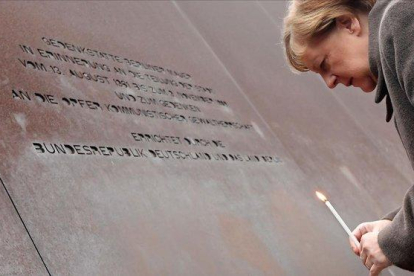 La canciller alemana coloca una vela en el Memorial del Muro de Berlín.-AFP / TOBIAS SCHWARZ