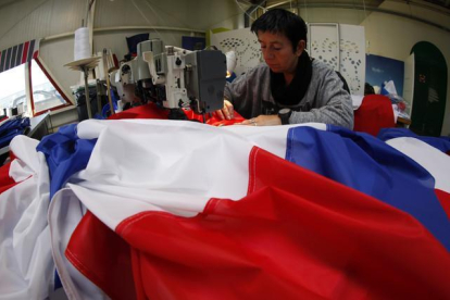 Una trabajadora de la empresa Doublet cose una bandera francesa, ayer en Lille.-AP / MICHEL SPLINGER