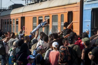 Decenas de inmigrantes y refugiados intentan subir a un tren en una estación de Macedonia con destino a Serbia, el martes.-