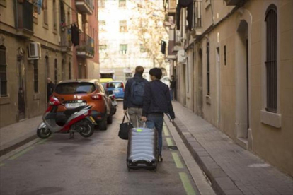 Dos turistas con su equipaje en una calle de la Barceloneta.-ALBERT BERTRAN