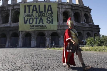 Un hombre vestido de centurión pasa frente al Coliseo romano.-REUTERS / STEFANO RELLANDINI