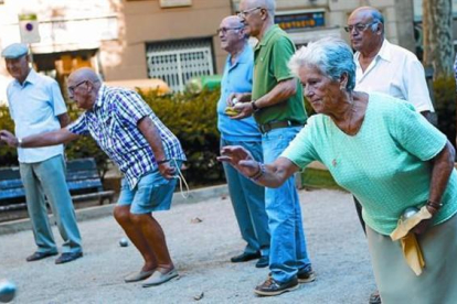 Un grupo de pensionistas juega a petanca en un parque.-ALBERT BERTRAN
