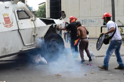 Un manifestante yace bajo una tanqueta policial en Caracas.-FEDERICO PARRA