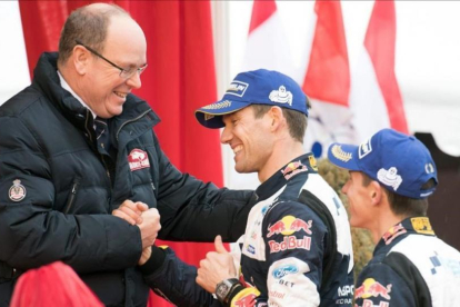 Sébastien Ogier estrecha la mano del príncipe Alberto de Mónaco junto a su copiloto, Julien Ingrassia, este domingo en Mónaco.-AFP / YANN COATSALIOU
