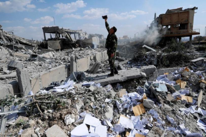 Un soldado sirio filma los escombros tras un ataque de las fuerzas estadounidenses, francesas y británicas el 14 de abril del 2018 para castigar al presidente Bashar el Asad por el uso de armas químicas contra civiles.-/ HASSAN AMMAR (AP)