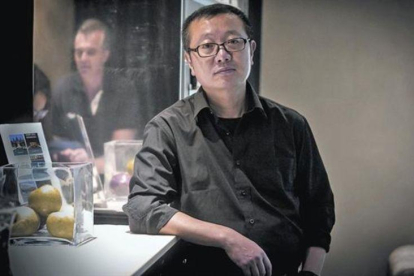 El escritor de ciencia ficción Liu Cixin posa en un céntrico hotel de Barcelona, el lunes. A la derecha, portada de 'El problema de los tres cuerpos' (Nova).-JOAN PUIG
