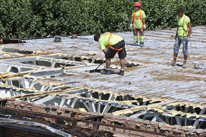 Varios operarios trabajan en el desmontaje del tejado de la Juventud. / VALENTÍN GUISANDE-