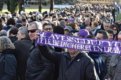 Un aficionado sostiene una bufanda de la Fiorentina durante el funeral de Davide Astori-MAURIZIO DEGL INNOCENTI
