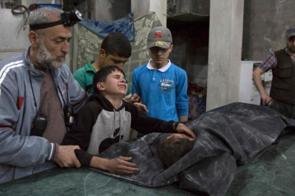 Un niño sirio es consolado mientras llora junto al cuerpo de su hermano pequeño que murió en el ataque aéreo del régimen de Bashar al Asad al hospital de Al Quds.-AFP / KARAM AL-MASRI
