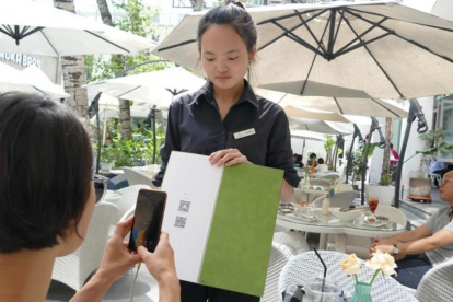Una joven paga su consumición en un terraza de Shanghái con el teléfono móvil.-ADRIÁN FONCILLAS