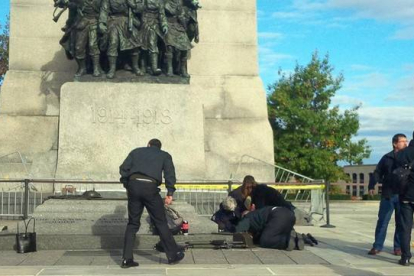 Unos soldados atienden a un compañero herido, ante el monumento de los veteranos de guerra en Ottawa.-