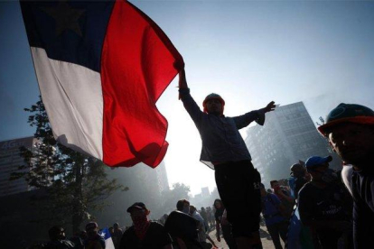 Una personas porta la bandera de Chile en medio de las protestas sociales.-EFE